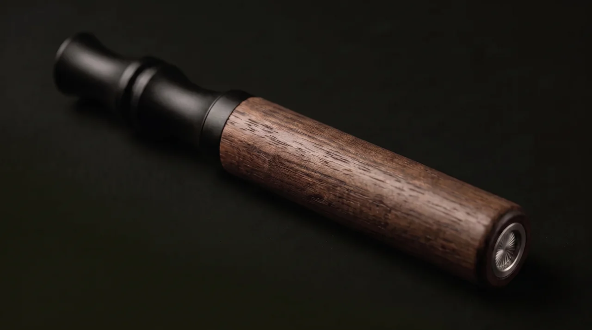 The Hale device lying on a dark surface, wooden body and matte black mouthpiece